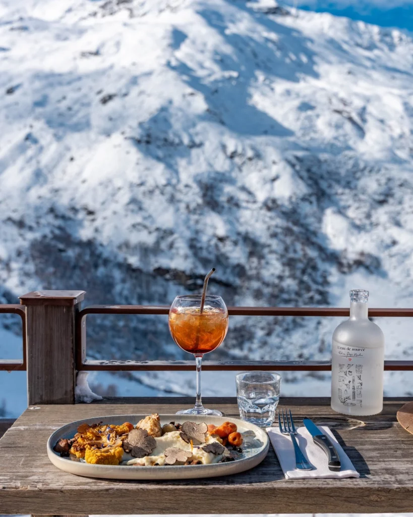 ssiette et cocktail sur la terrasse de Chez Pépé Nicolas, face aux montagnes enneigées de la vallée des Belleville.